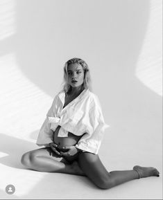 a black and white photo of a woman sitting on the ground with her legs crossed