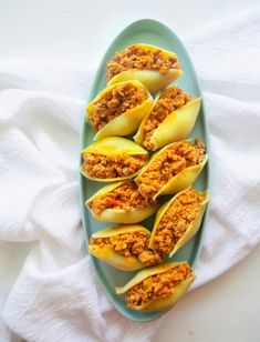 stuffed shells filled with meat and sauce on a blue plate next to a white towel