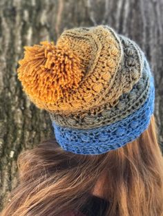 a woman wearing a crocheted hat standing next to a tree