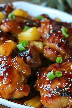 a white bowl filled with chicken and pineapples covered in sesame seed flakes