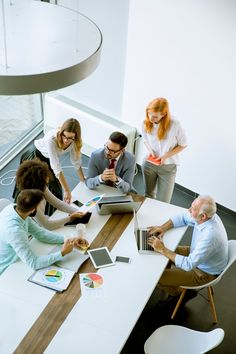 four people sitting at a table working on laptops