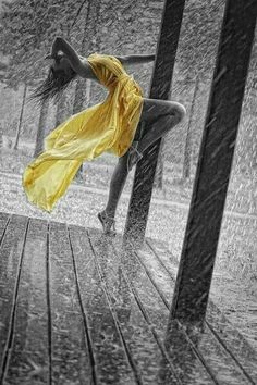 a woman dancing in the rain on a wooden deck