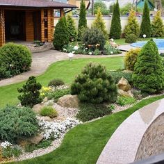 a garden with trees and bushes in front of a house