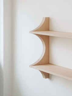 two wooden shelves on the wall with white walls in the background and one shelf is empty