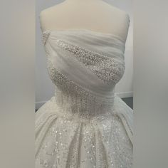 a white wedding dress is displayed on a mannequin headdress with beading