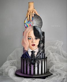 a cake with a woman's face on top of it, and a hand reaching for the cake