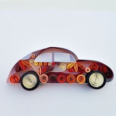 a car made out of paper with circles on the side and wheels painted red, orange, yellow and white