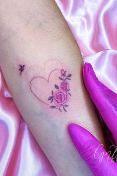 a woman's arm with a rose and heart tattoo on it