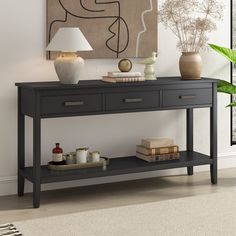 a black table with two lamps and some books on it next to a wall painting