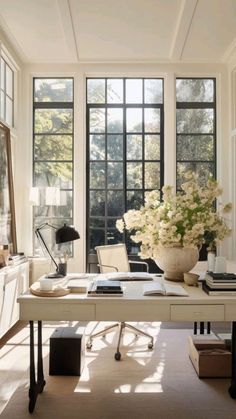 an office with large windows and a desk in front of the window is filled with flowers