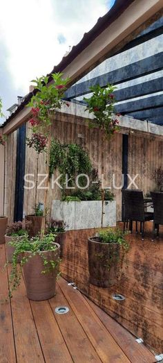 a wooden deck with potted plants on it and an awning in the background