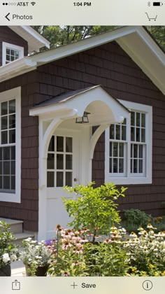 a brown house with white trim on the front door and windows, along with flowers