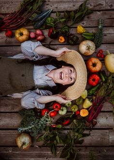 a woman wearing a hat surrounded by fruits and vegetables