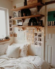 a white bed sitting in a bedroom next to a wooden shelf filled with books and other items