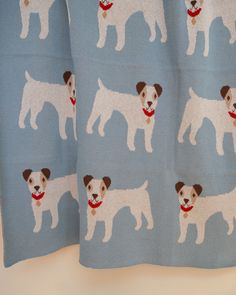 a blue and white dog print curtain with brown spots on it's face, in front of a light blue background