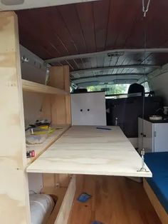 the inside of a van with wood shelves and blue mattresses on it's sides