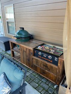 an outdoor entertainment center with a grill on it's side table next to a chair