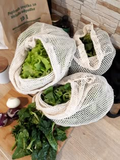 two mesh bags filled with green vegetables on top of a wooden table