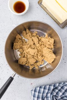 a metal bowl filled with food on top of a counter next to a knife and butter