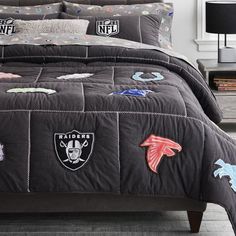 a bed covered in black comforter and pillows with embroidered animals on it, next to a night stand