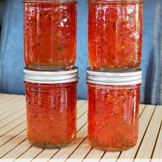 three jars filled with red liquid sitting on top of a wooden table