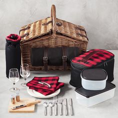 a picnic basket with utensils, wine glasses and napkins next to it