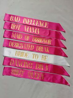 five pink sashes with gold lettering on them