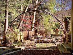 an arch in the middle of a garden with tables and chairs set up on it