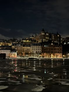 the city is lit up at night with lights reflecting in the water and ice floes on the ground