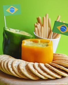 a plate with crackers, cheese and vegetables on it in front of a green wall