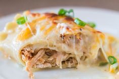 a white plate topped with lasagna covered in meat and cheese, garnished with green onions