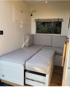 a couch bed in the corner of a room with drawers underneath it and a window