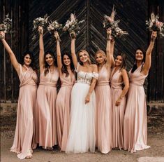 a group of bridesmaids holding bouquets in front of an old barn door