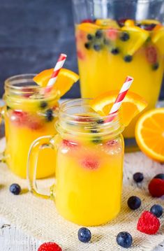 three mason jars filled with lemonade, blueberries and orange slices