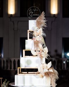 a wedding cake with feathers and flowers on top