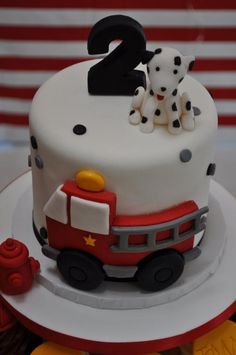 a birthday cake with a fire truck and dog on top is decorated to look like the number two