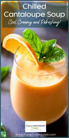 a glass filled with orange juice and garnished with basil leaves on the side