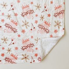 a white blanket with pink and brown flowers on it, laying on top of a table