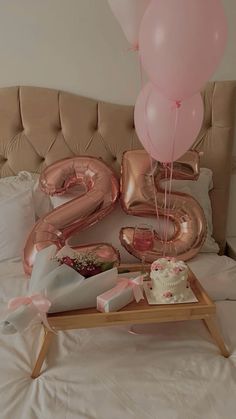 a birthday cake and balloons on a bed