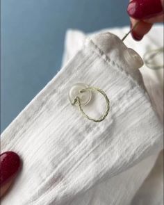 a woman is holding onto a piece of cloth with a small ring on top of it