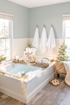 a bathroom decorated for christmas with white towels hanging on the wall and lights in the bathtub