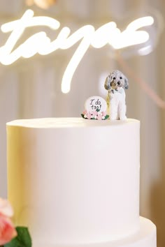 a small dog figurine sitting on top of a white frosted wedding cake