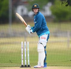 a man holding a cricket bat on top of a field