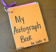 an orange book with the words my autograph book written on it and a purple ribbon