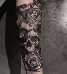 a black and white tattoo with roses on the arm, skull and crossbones