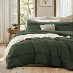 a bed with green comforter and white pillows