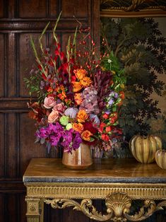 a vase filled with lots of colorful flowers on top of a table next to a wall