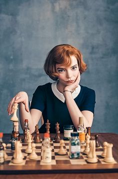 a woman is sitting at a chess board