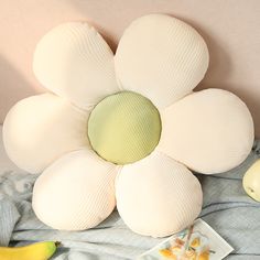 a flower shaped pillow sitting on top of a bed next to a banana and other items