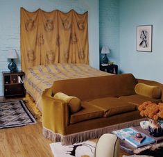 a bedroom with a bed, couch and coffee table in front of the bed is decorated with orange flowers